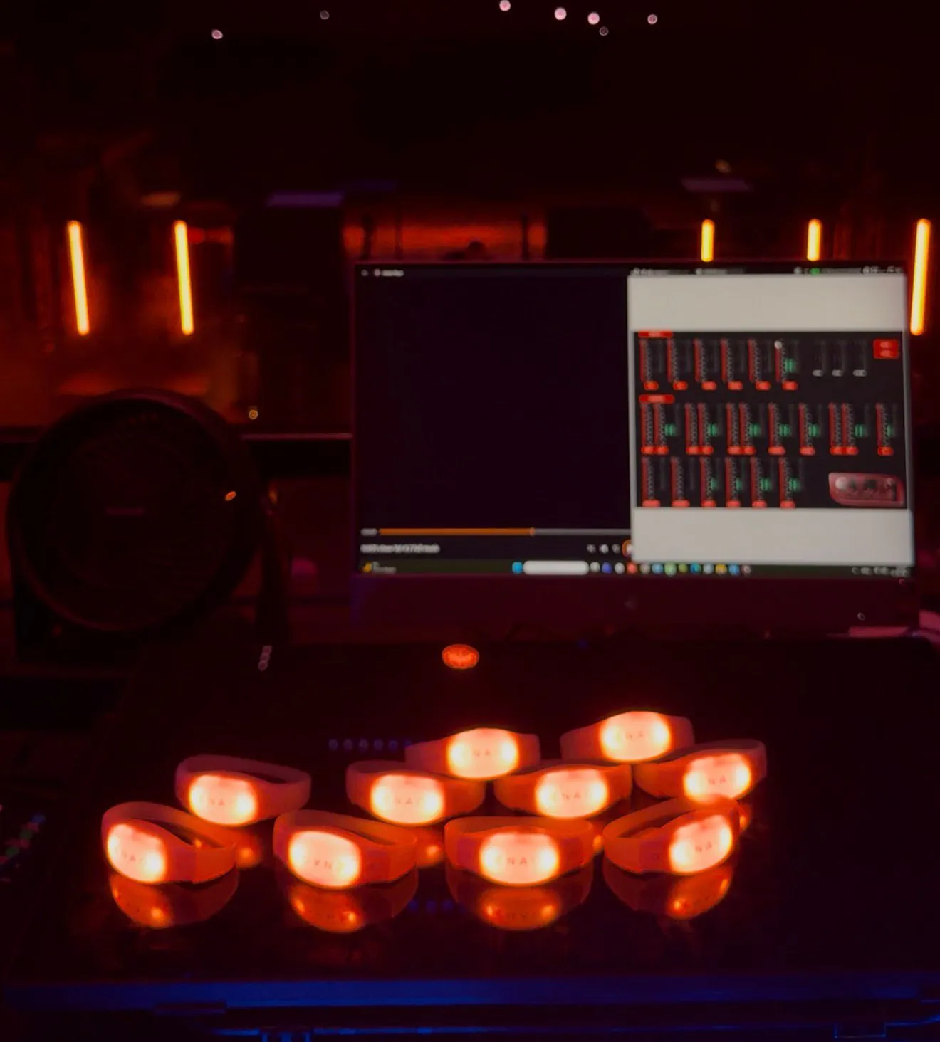 Silicone wristbands glowing orange in front of the show computer during programming for Naos International