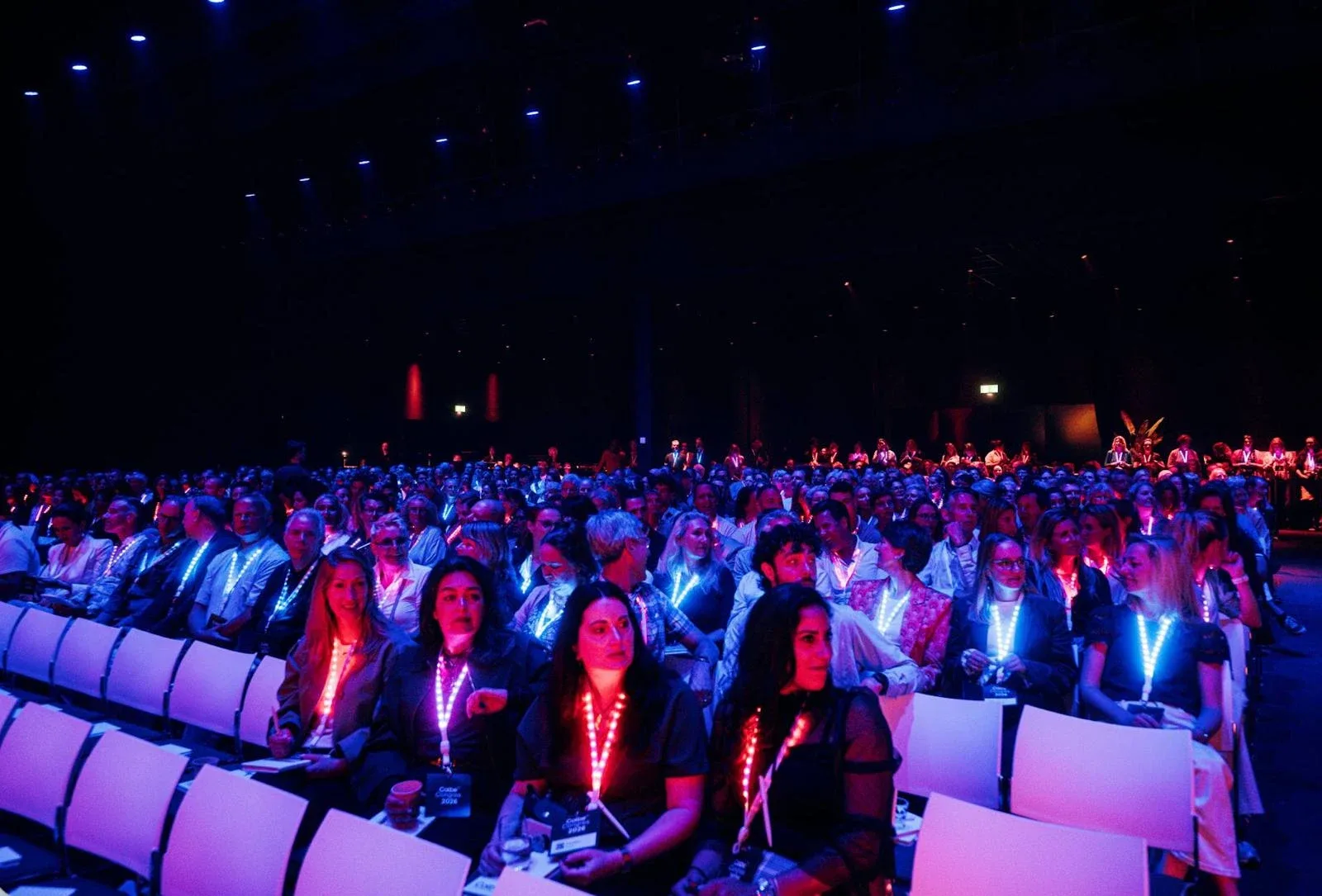 A full congress hall in the Netherlands, attendees wearing LED lanyards lit red and blue